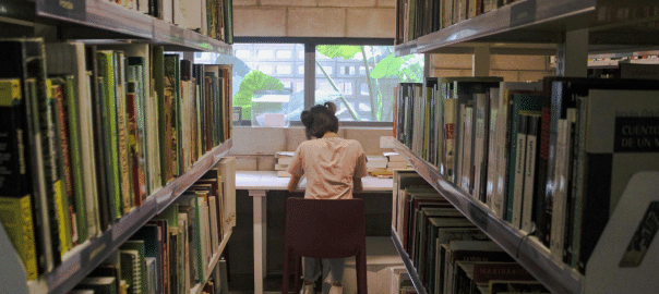Student in the library surrounded by books